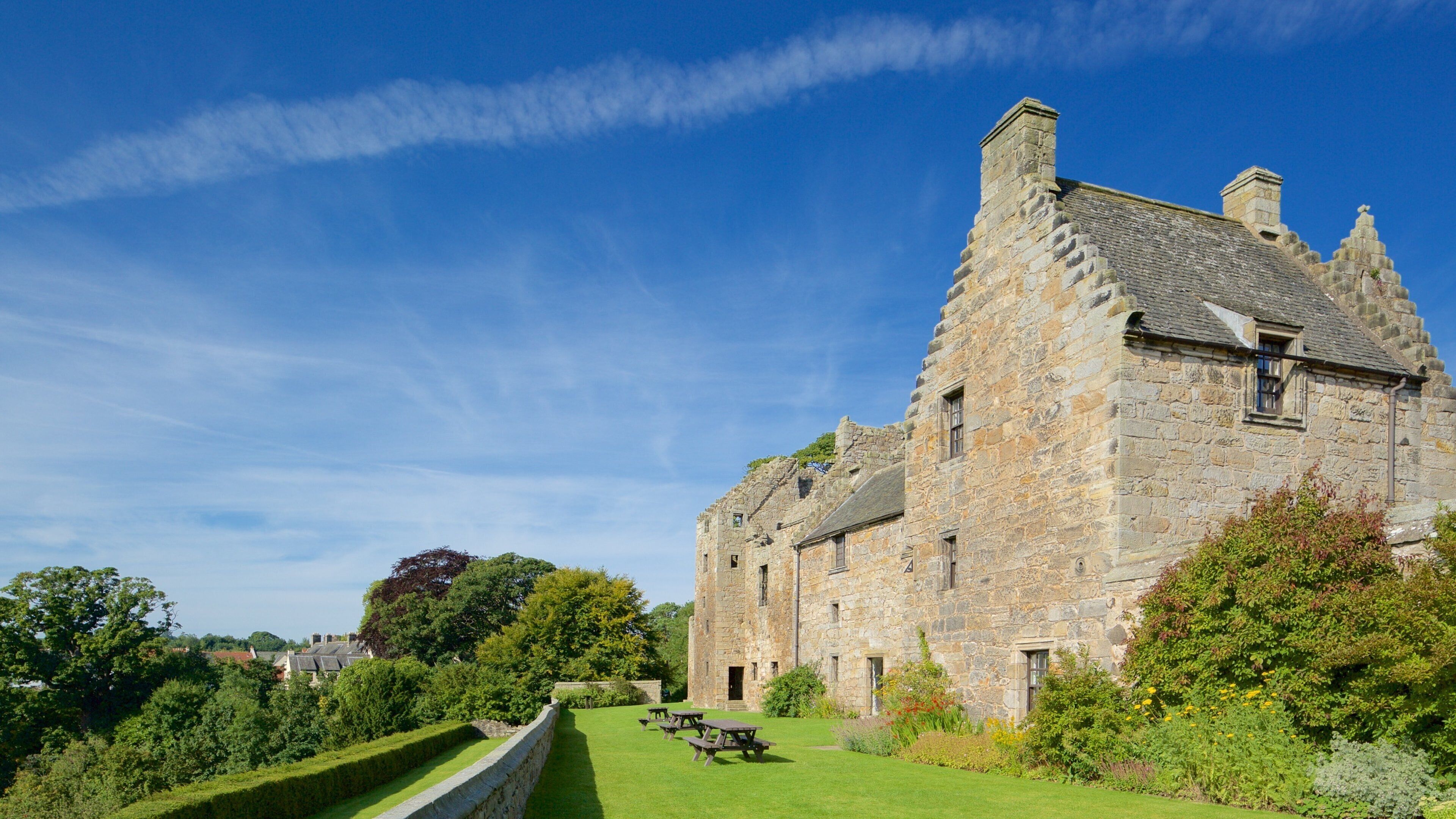 A historic stone building with a well-maintained lawn and picnic tables.