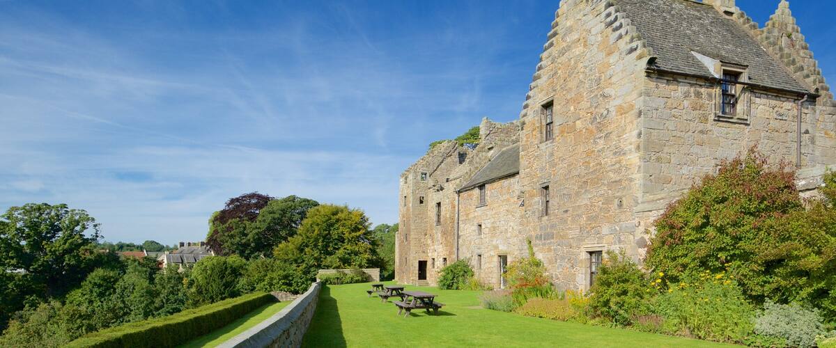 A historic stone building with a well-maintained lawn and picnic tables.