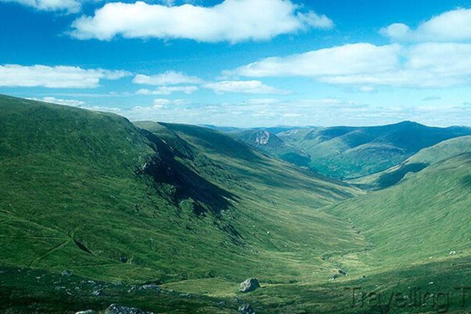 Une vallée aux collines douces, avec une chaîne de montagnes lointaine, le tout sous un ciel dégagé.
