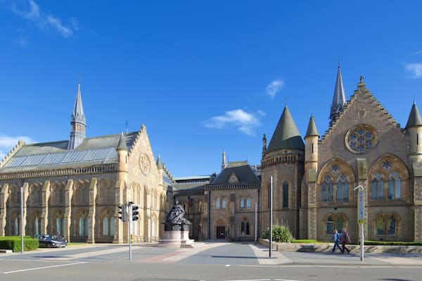 A historic church with pointed towers and a statue in front.