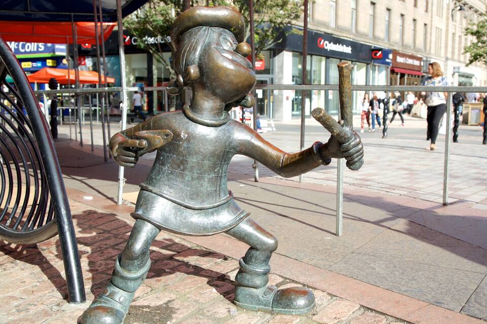 A bronze statue of a man holding a baseball bat in a public square.