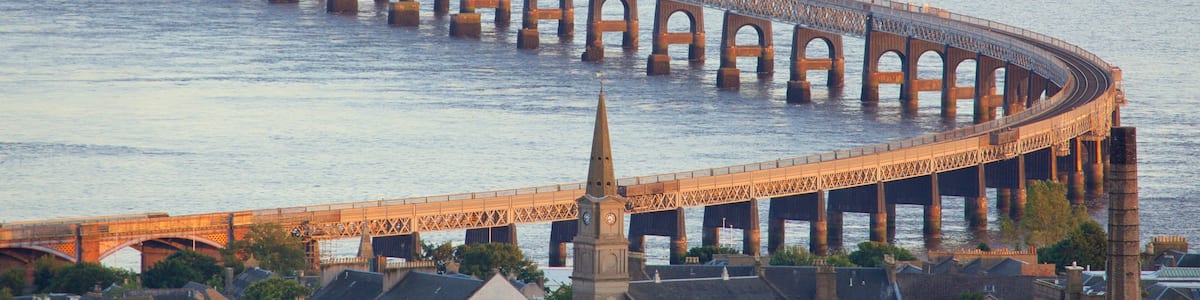 A large, arched bridge over a body of water, with buildings and a church in the foreground.