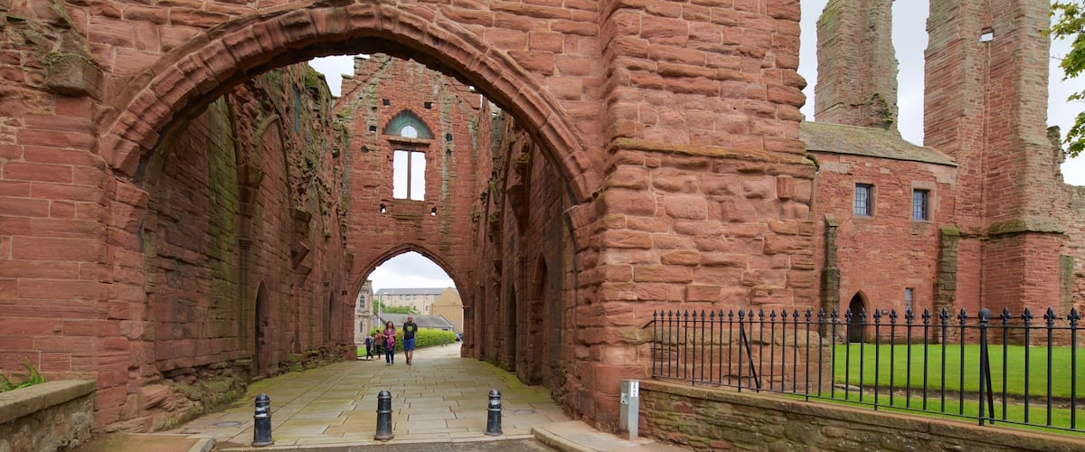 An ancient stone archway leading into a historic building with tall towers.