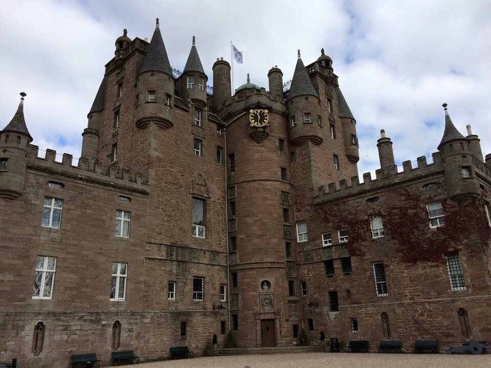 A large, historic castle with multiple towers and a central clock tower.