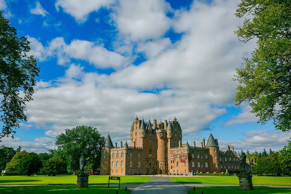 A large castle with multiple towers and a well-maintained lawn.
