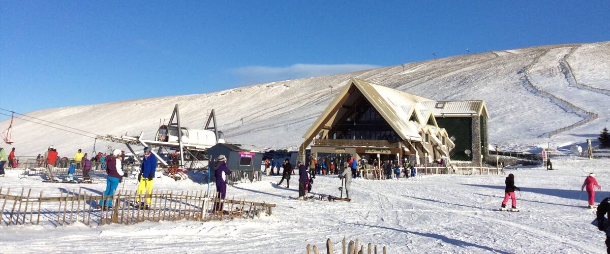 A ski resort with a wooden lodge, a ski lift, and a snowy mountain slope.