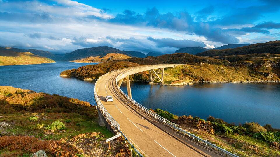 A bridge over a lake with mountains in the background.
