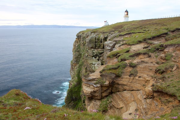 Dunnet Head Lighthouse which includes a lighthouse and rocky coastline