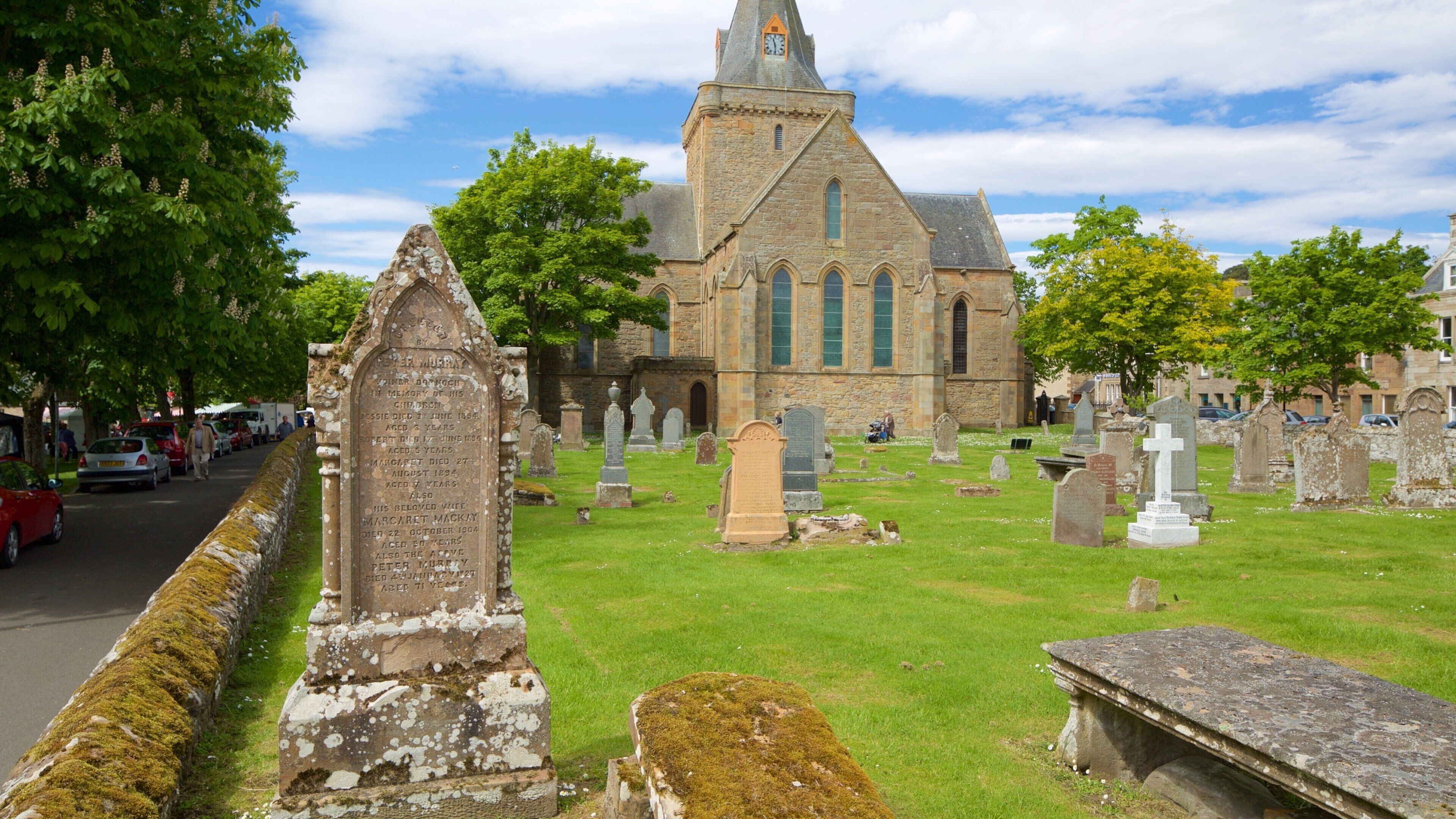 A church with a tall tower and a graveyard with numerous headstones.