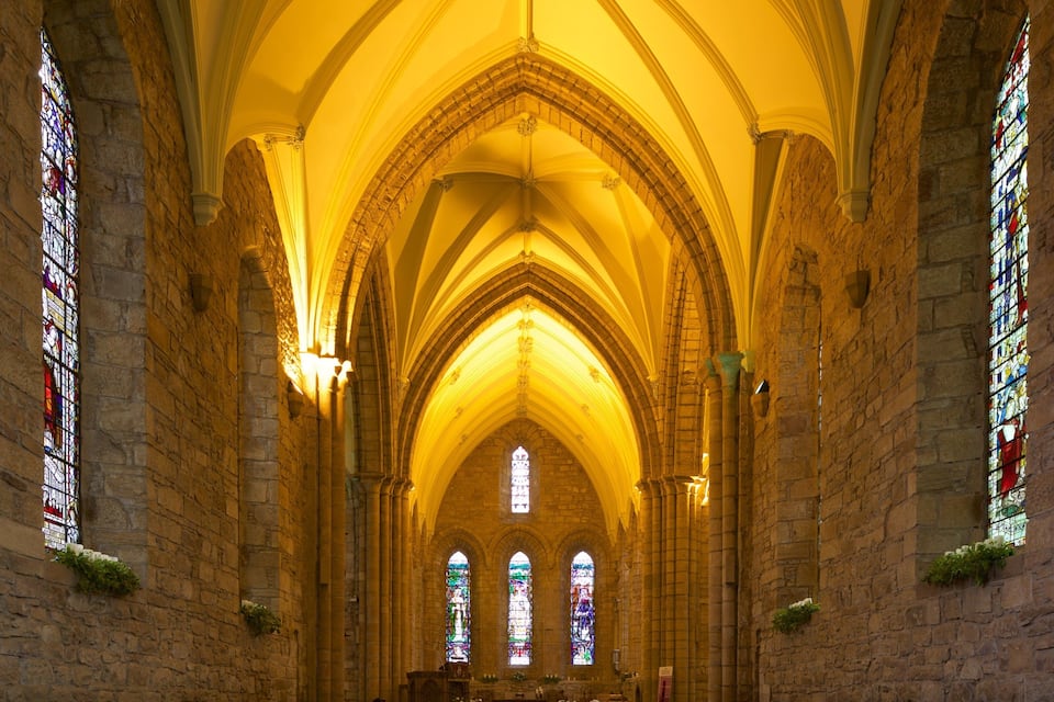 A cathedral interior with Gothic arches, stained glass windows, and stone walls.