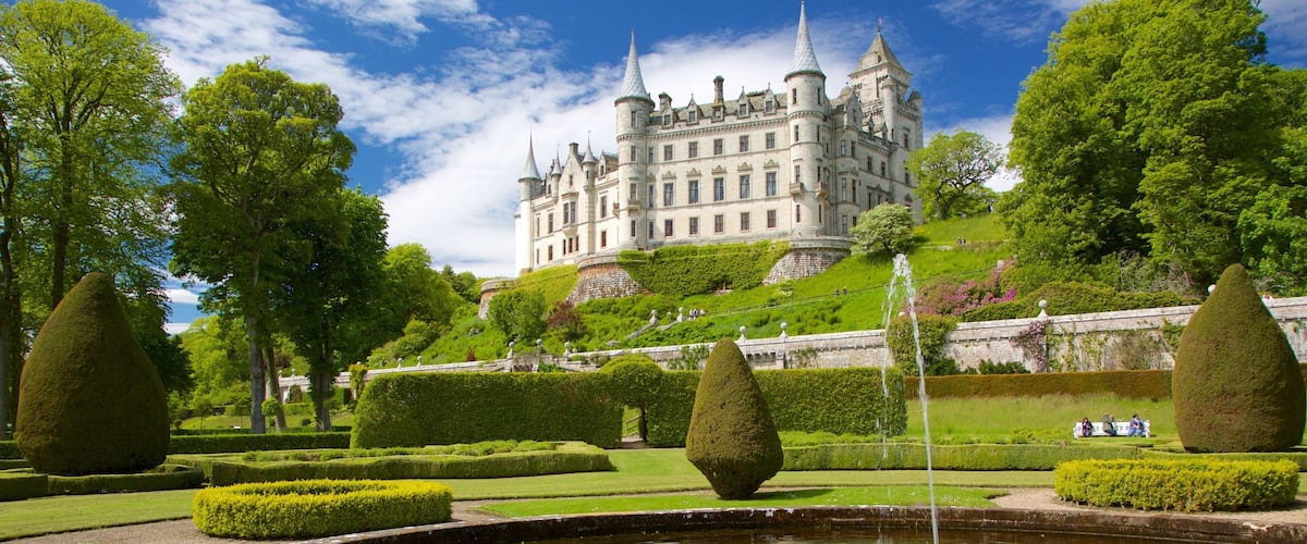 A castle on a hill with a fountain in the foreground.