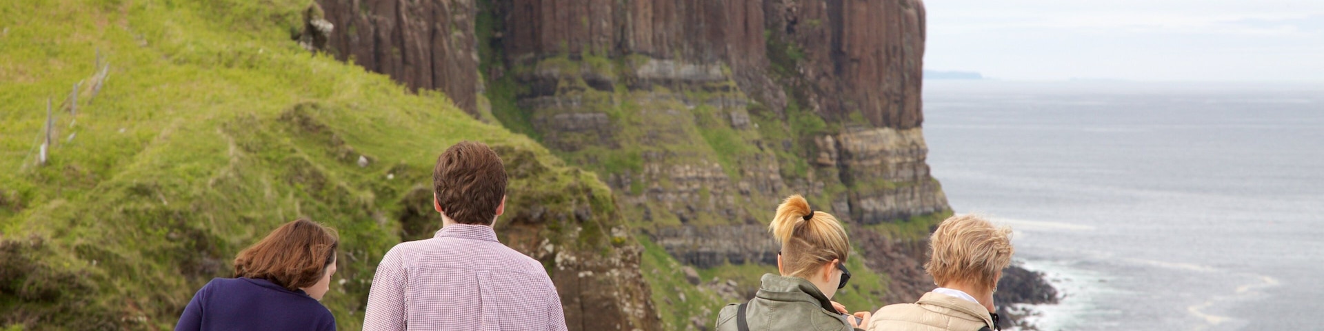 Kilt Rock mostrando litoral rochoso e paisagens assim como uma família