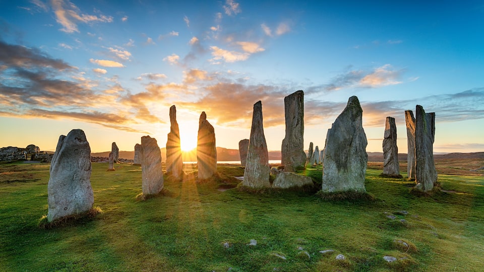 A stone circle with the sun setting in the background.