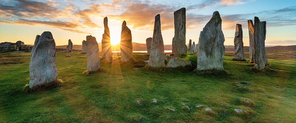 A stone circle with the sun setting in the background.