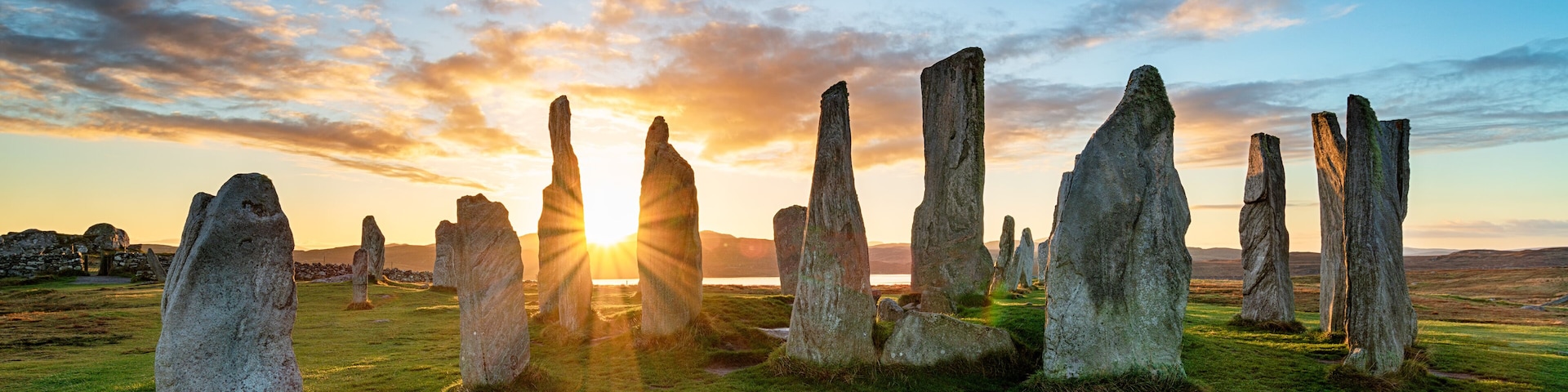 A stone circle with the sun setting in the background.