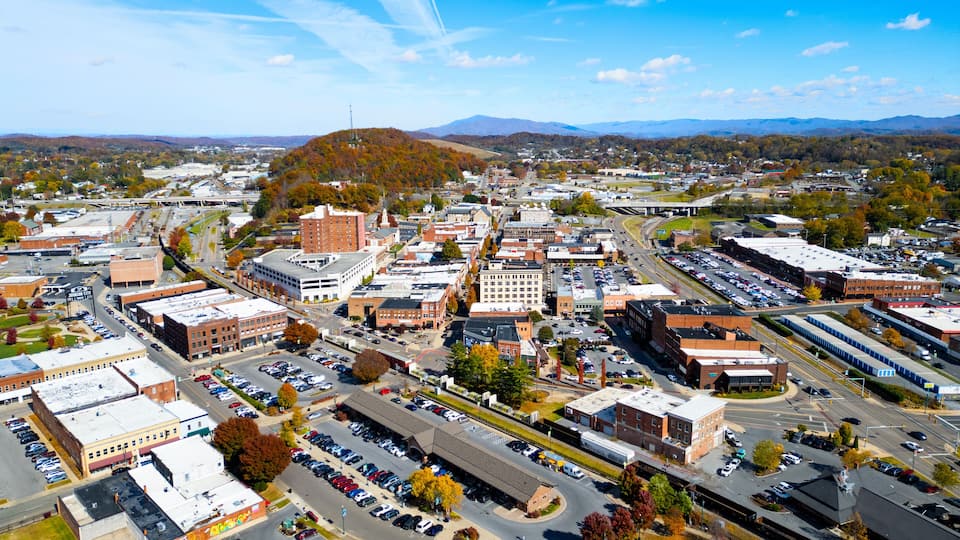 A cityscape with a prominent hill, various buildings, and a parking lot.