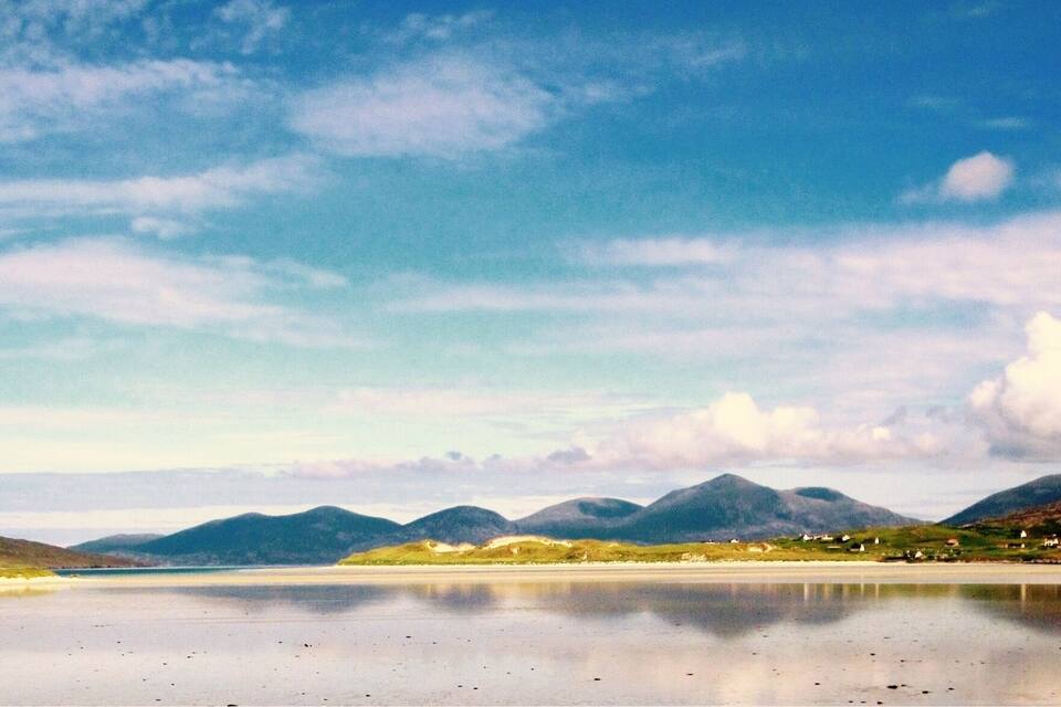 A calm lake with mountains in the background and a clear sky.