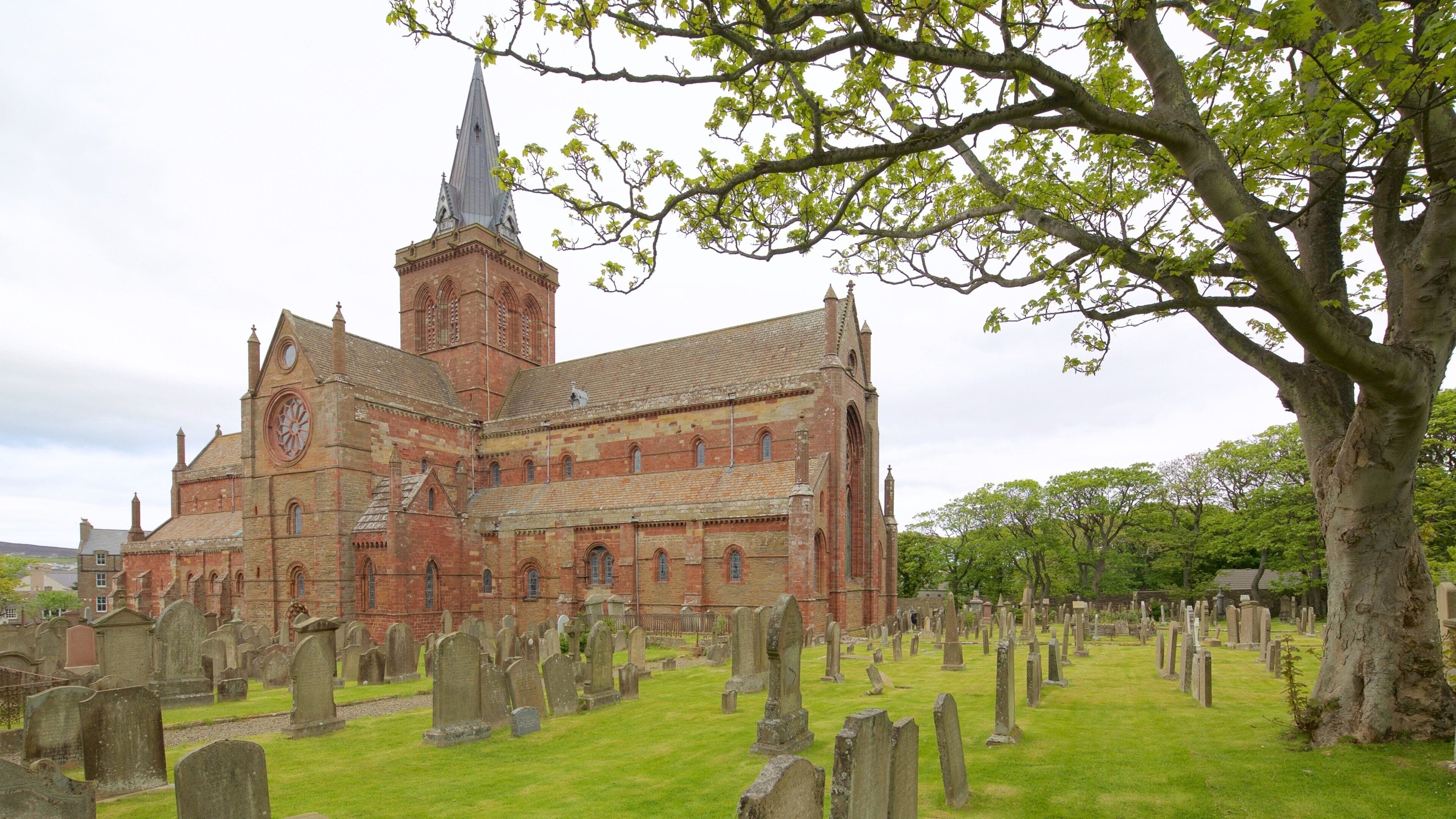 A historic church with a tall spire and a cemetery in the foreground.