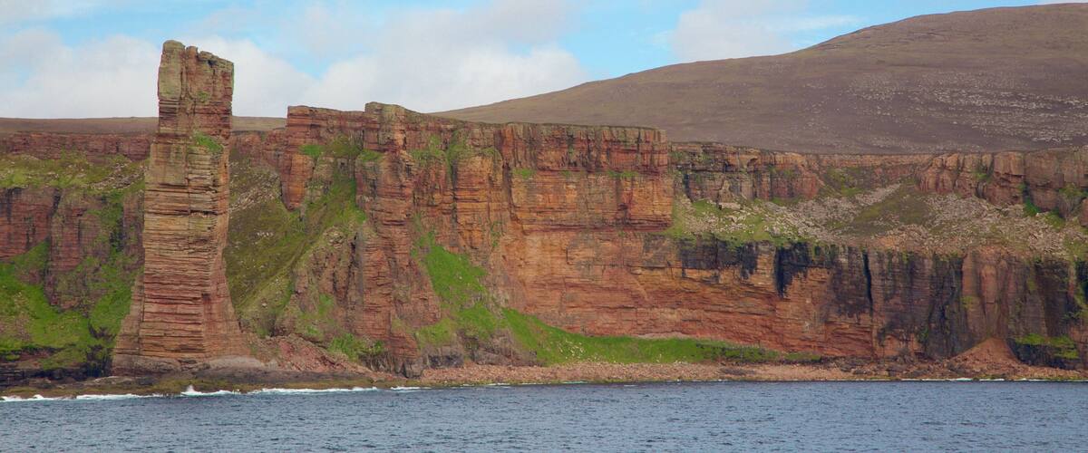 A coastal cliff with a prominent vertical rock formation.