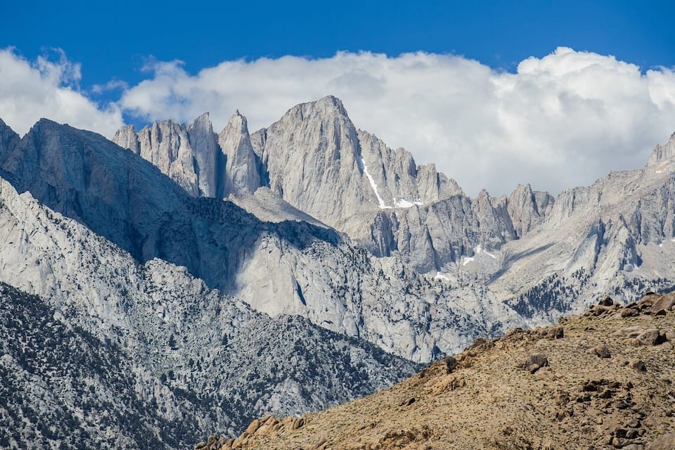 Una serralada muntanyosa escarpada amb pics afilats i un cel blau clar.