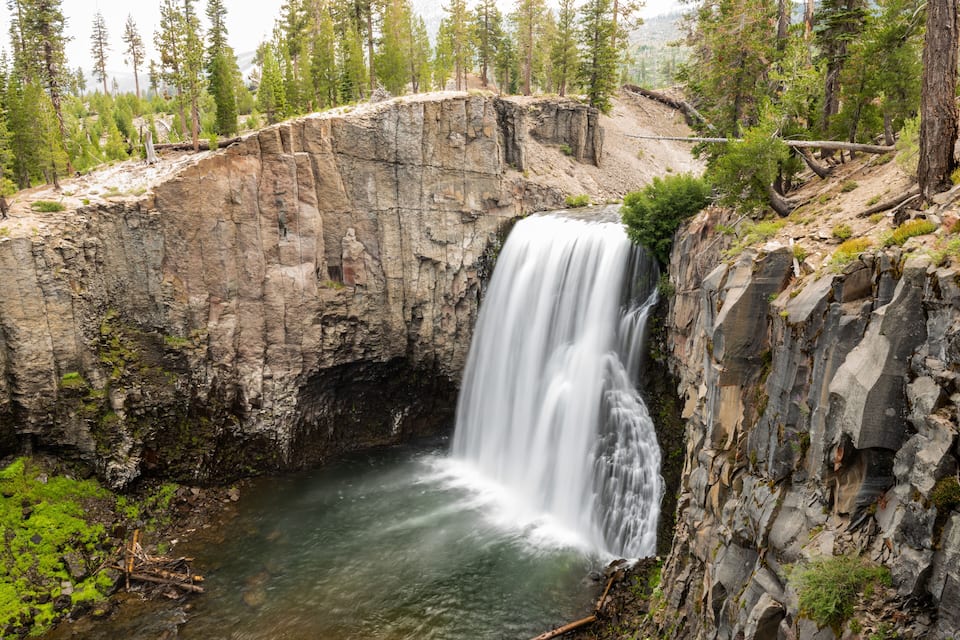A waterfall cascading over a rocky cliff surrounded by trees.