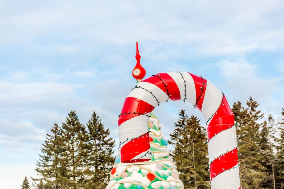 A large candy cane structure with a red top, surrounded by trees.