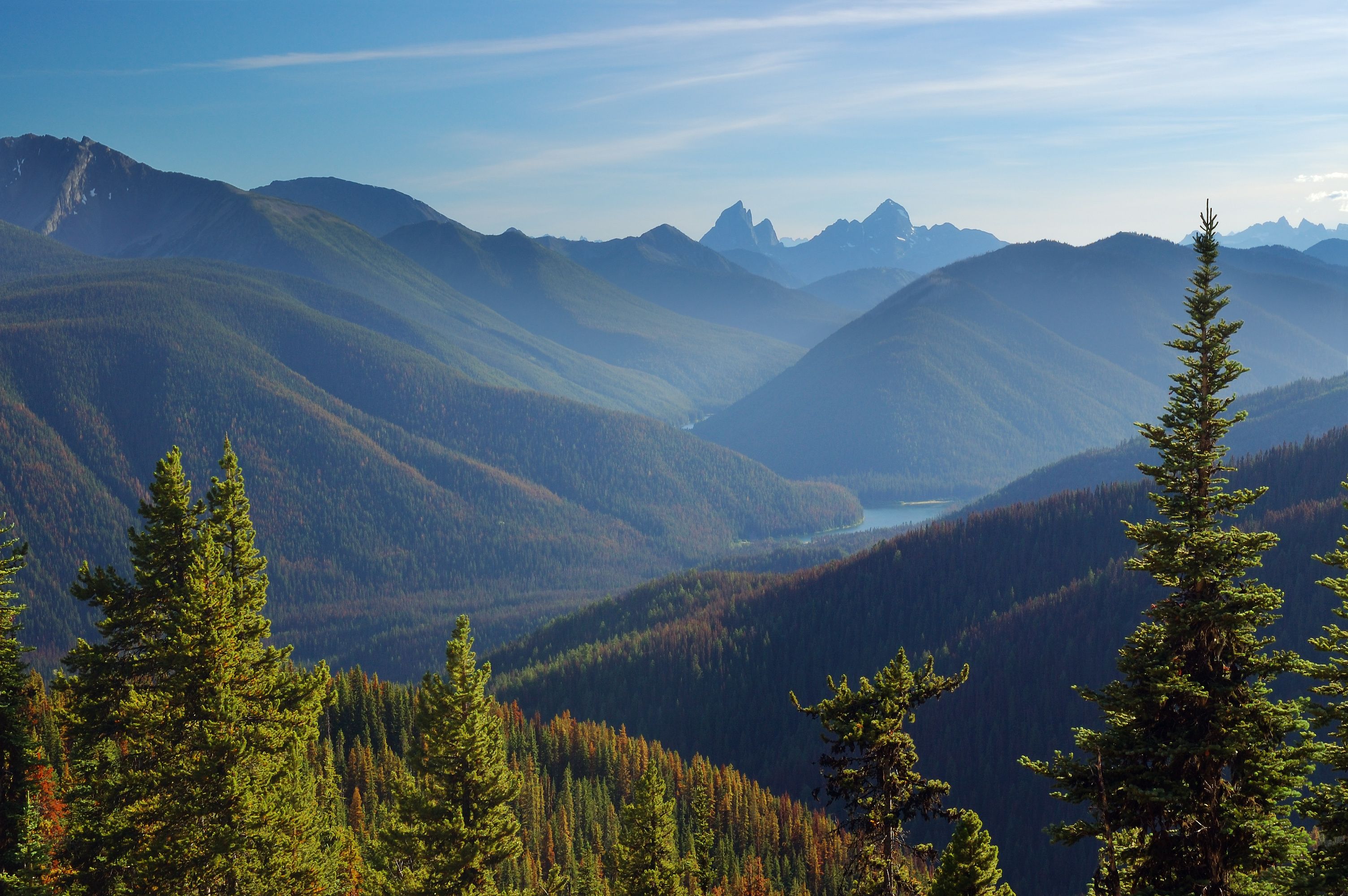 A mountainous landscape with dense forests and a clear sky.