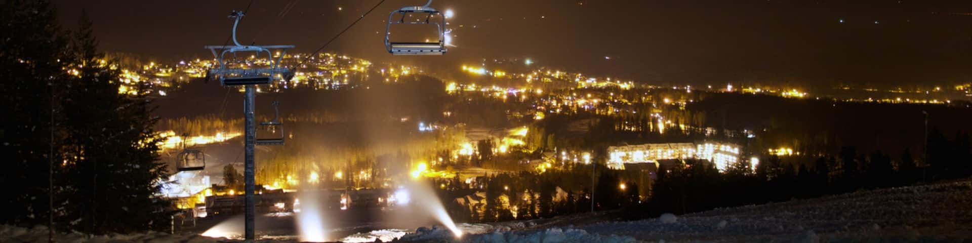 A snow-covered road with a ski lift in the background.
