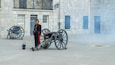 Een historisch gebouw met stenen muren, een kanon en een uniform geklede bewaker.