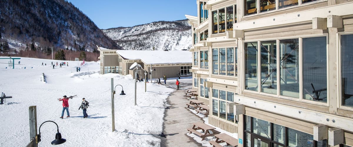 A snow-covered ski resort with wooden buildings and a clear blue sky.