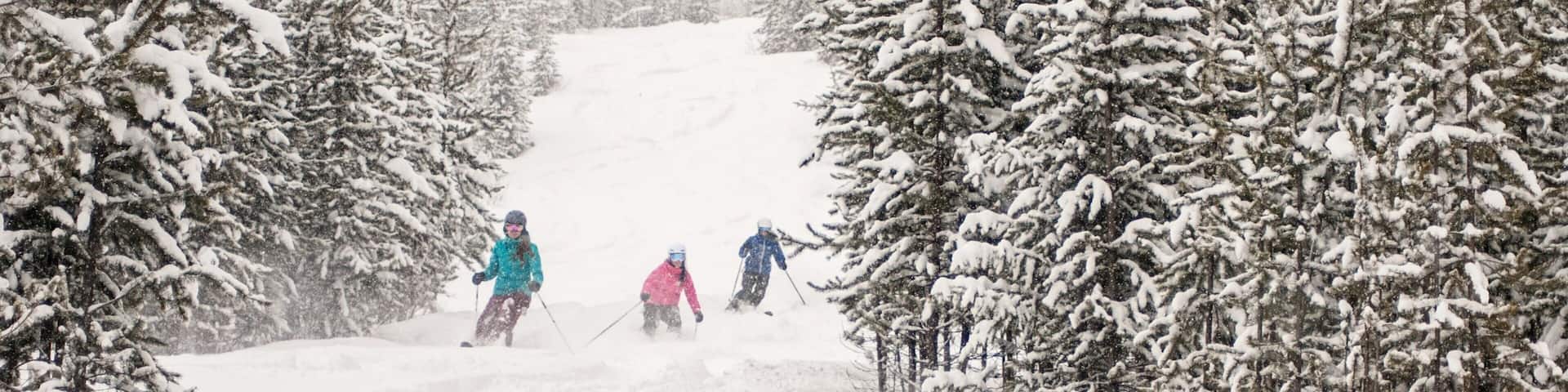 A snowy ski slope with skiers descending.