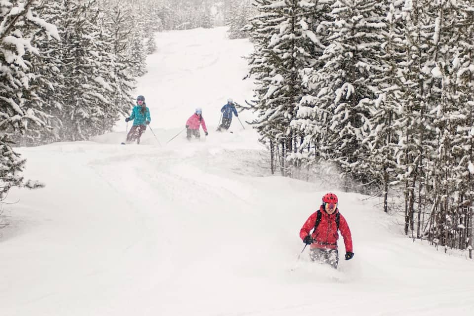 Una pista de esquí nevada con esquiadores descendiendo.