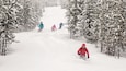 A snowy ski slope with skiers descending.