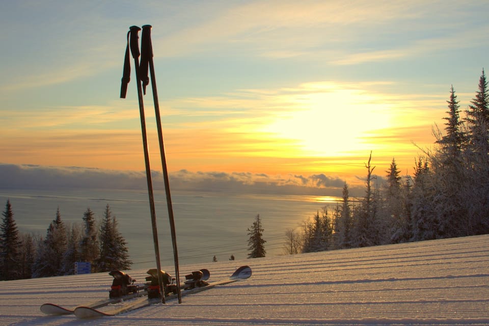 A snowy ski slope with a sunset in the background.
