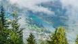A mountainous landscape with a lake, forested areas, and a small town.