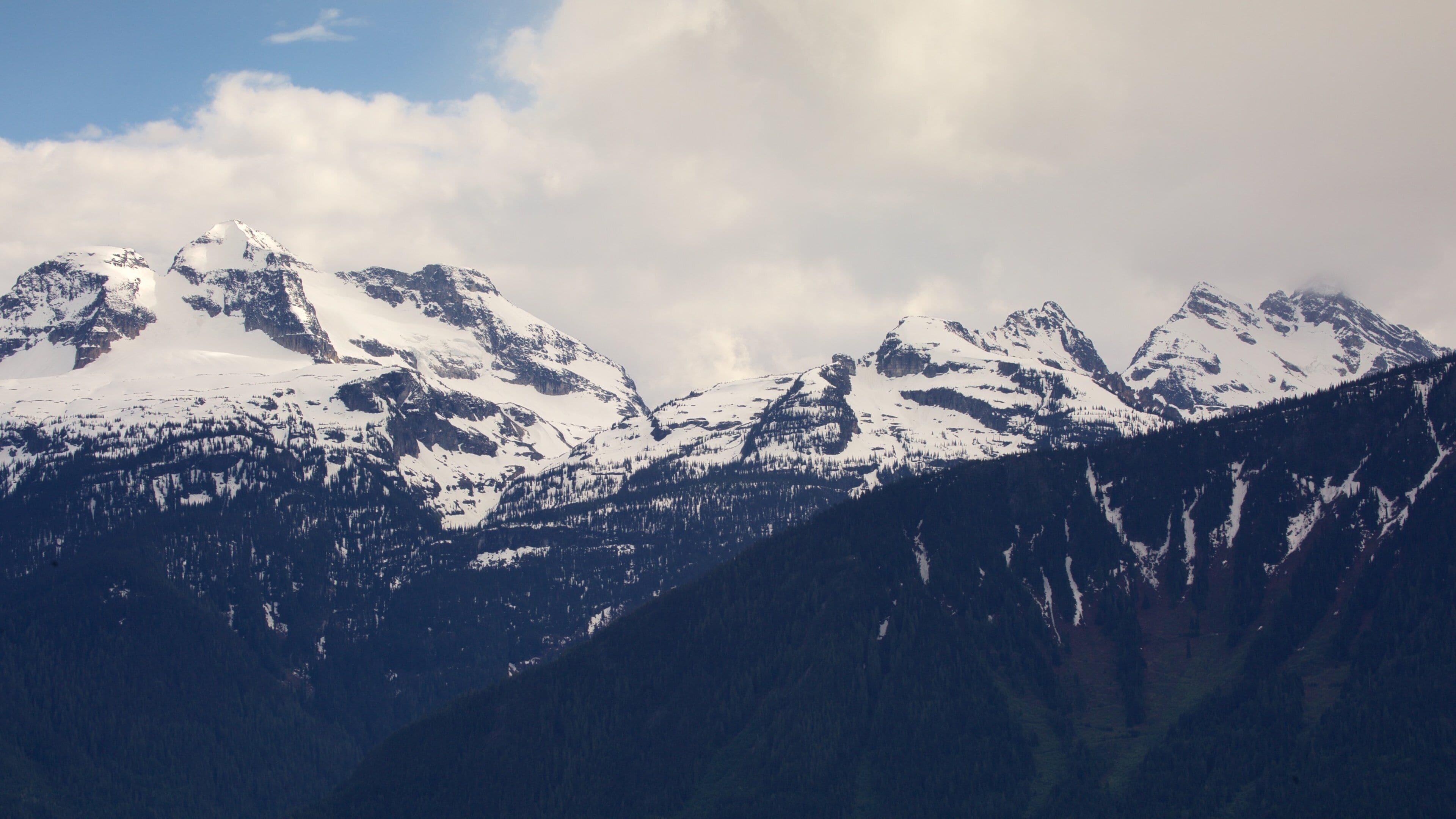 Snow-covered mountain peaks with a forested valley.