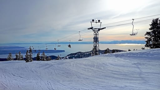 Cypress mountain in West Vancouver, BC. The romantic sunset. The view on the snowy downhill and ski chairlift with ocean / sea and island in the background.