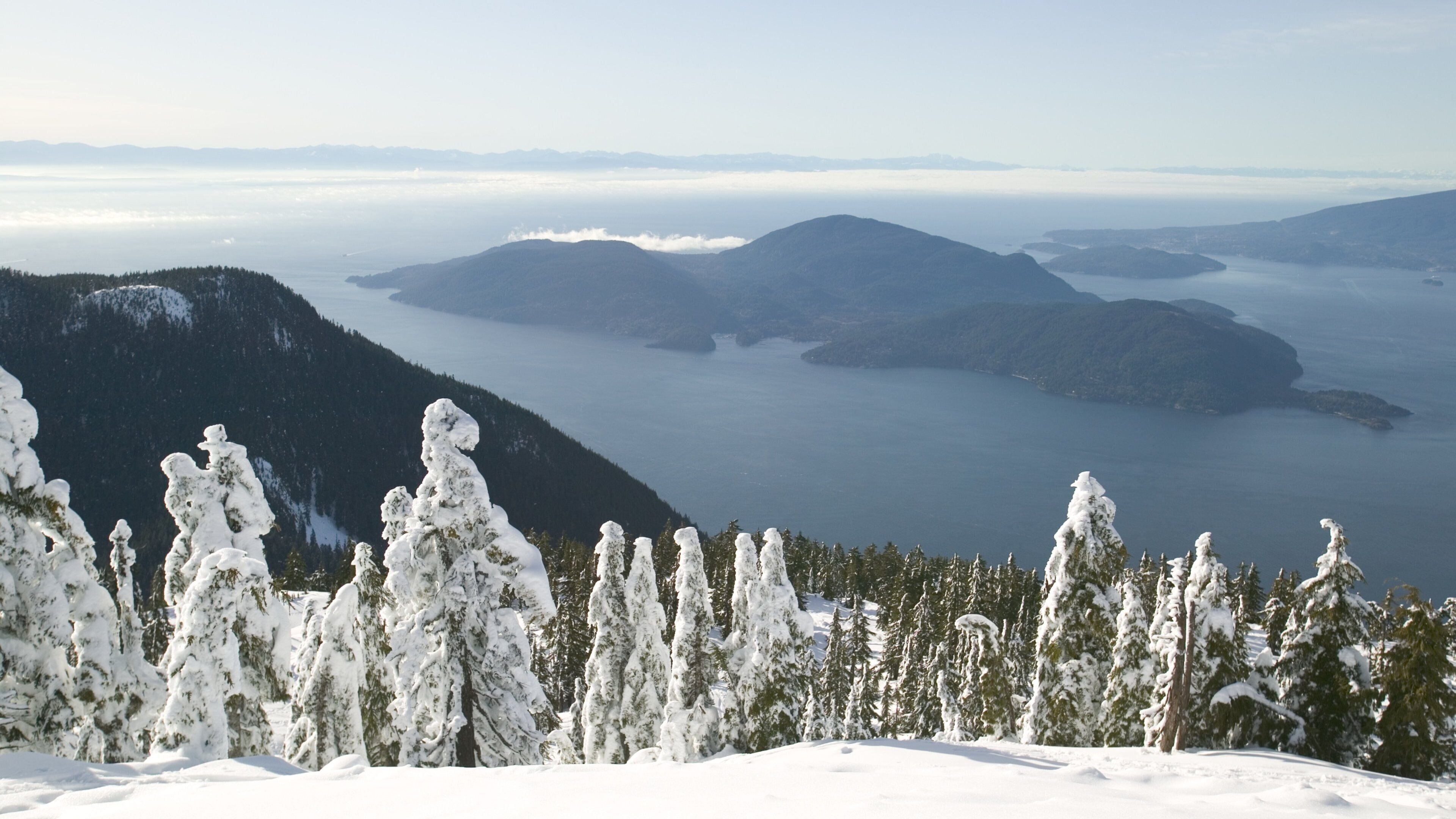 A snow-covered mountain landscape with a lake and distant mountains.