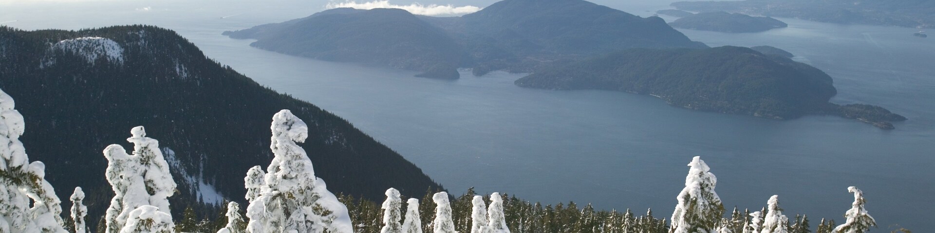A snow-covered mountain landscape with a lake and distant mountains.