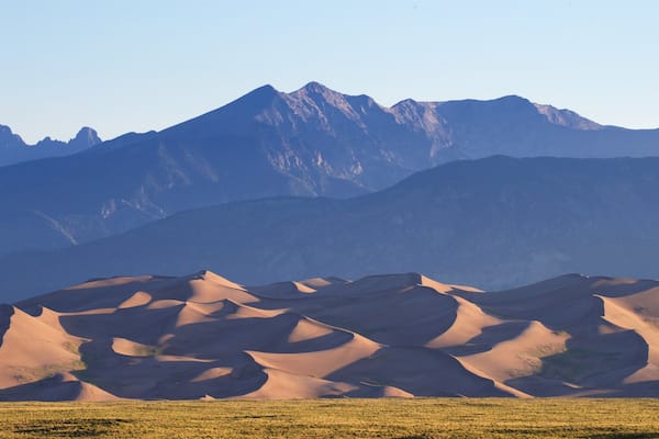 Sanddünen mit einem Bergmassiv im Hintergrund.