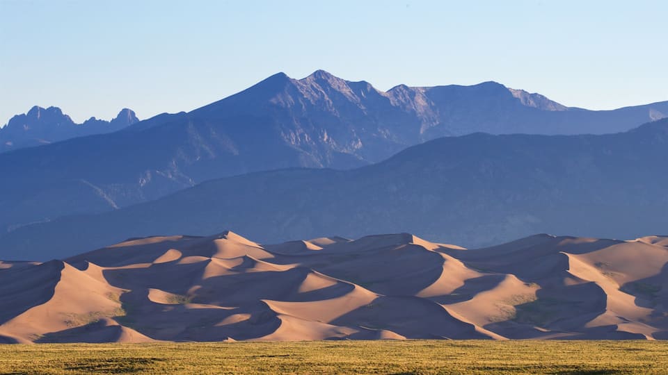 Sand dunes with a mountain range in the background.