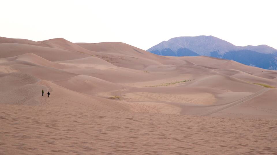 Sand dunes with two people walking.