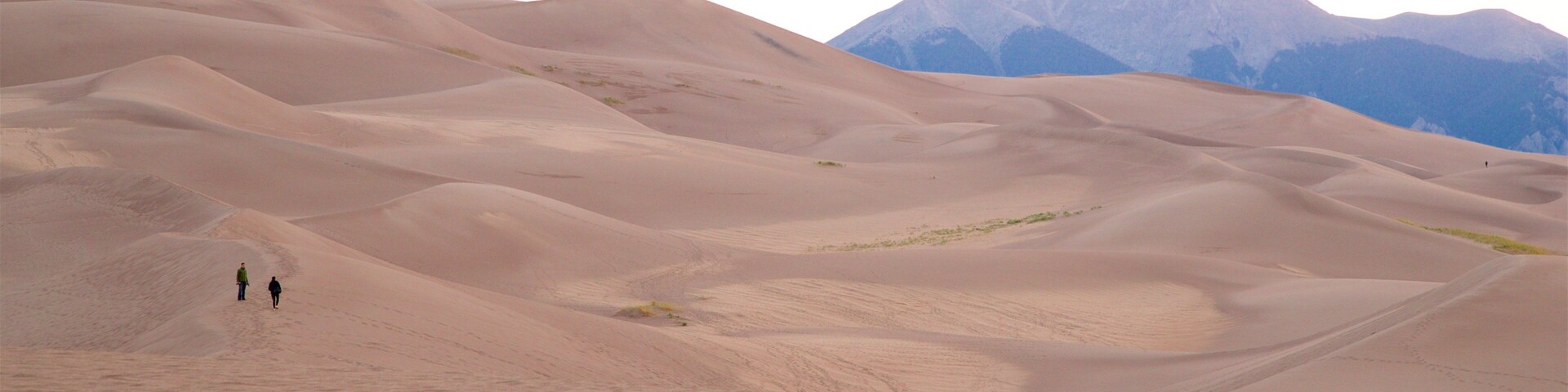 Dunas de arena con dos personas caminando.