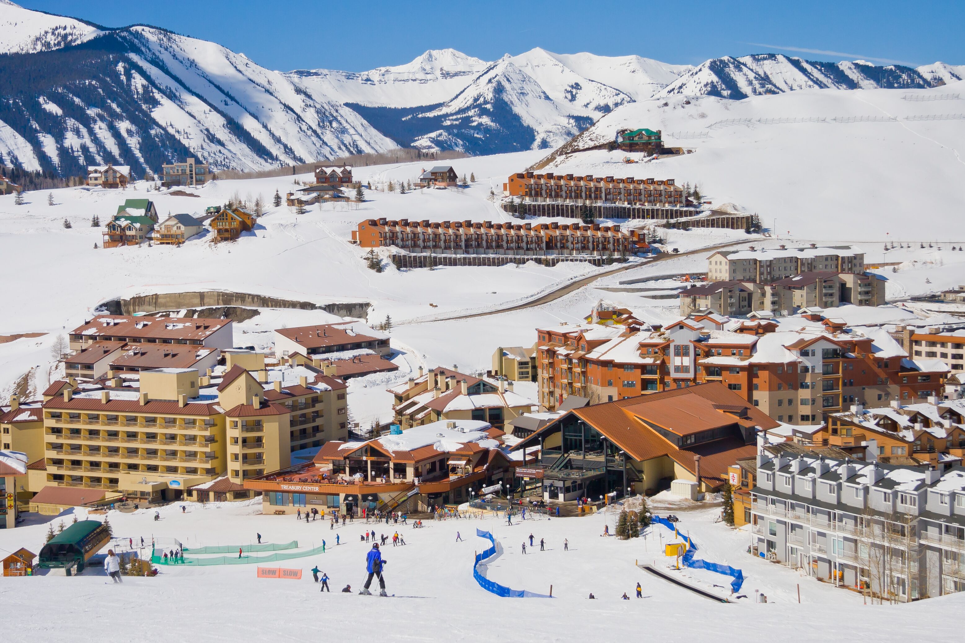 Une station de ski enneigée, avec des bâtiments, des pistes de ski et des montagnes en arrière-plan.
