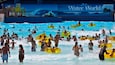 A crowded water park with inflatable tubes and a large sign reading "Water World".