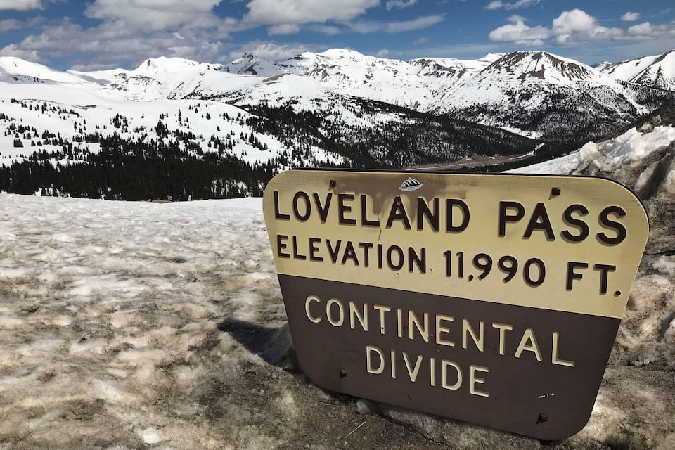 A sign indicating the Loveland Pass elevation at 11,990 feet and its location on the Continental Divide.