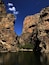 A canyon with steep rock walls and a calm river at its base.