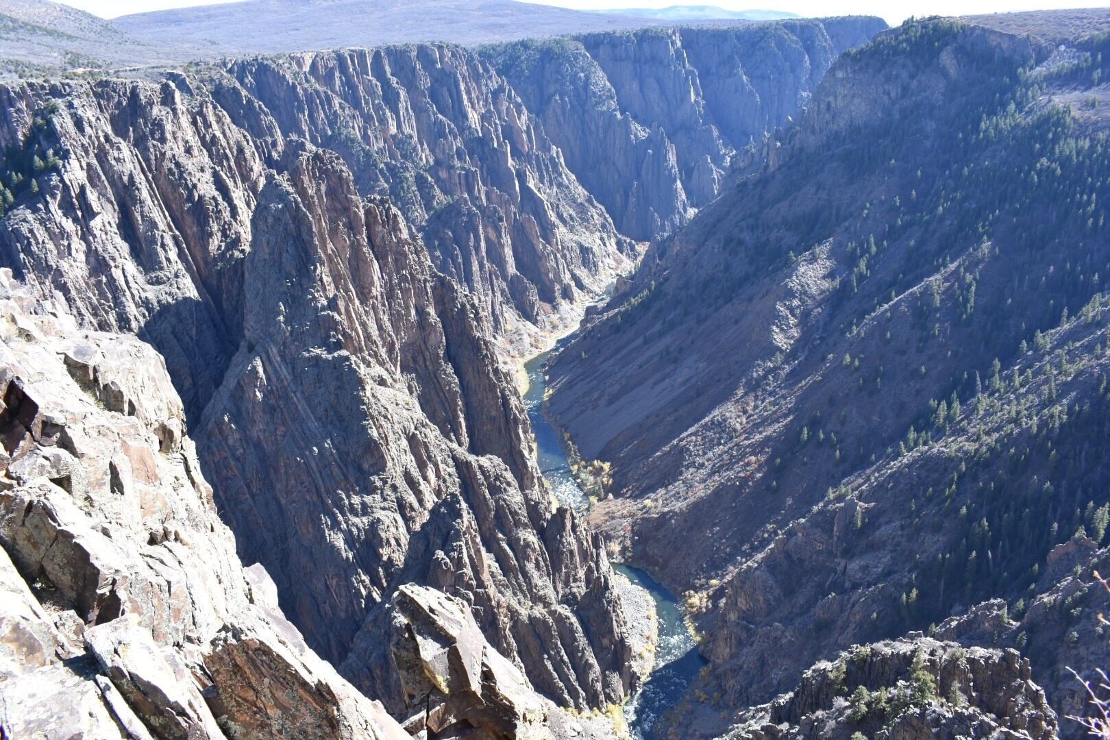 A deep canyon with steep, rugged cliffs and a narrow river running through it.