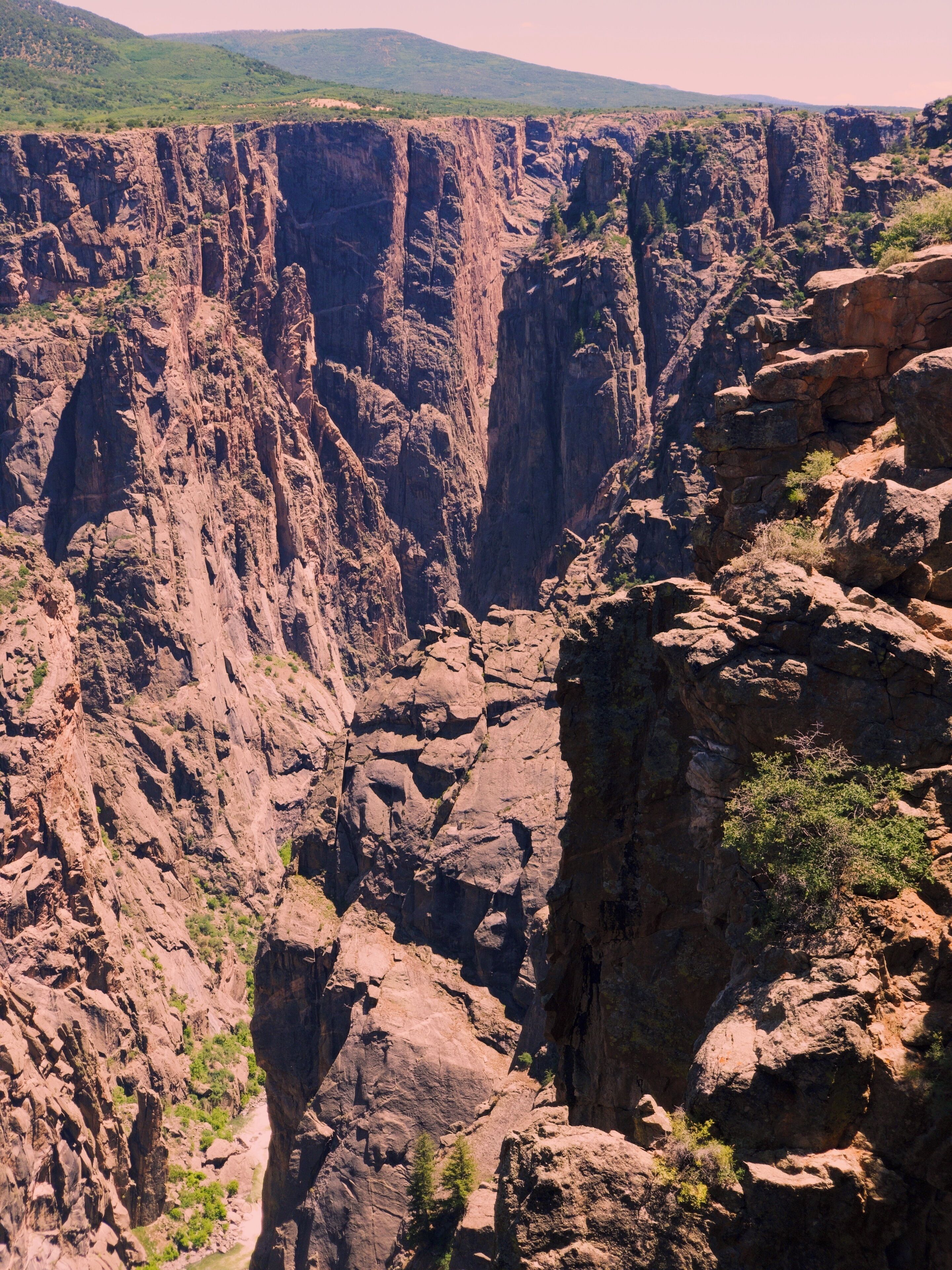 A canyon with steep rock walls and sparse vegetation.
