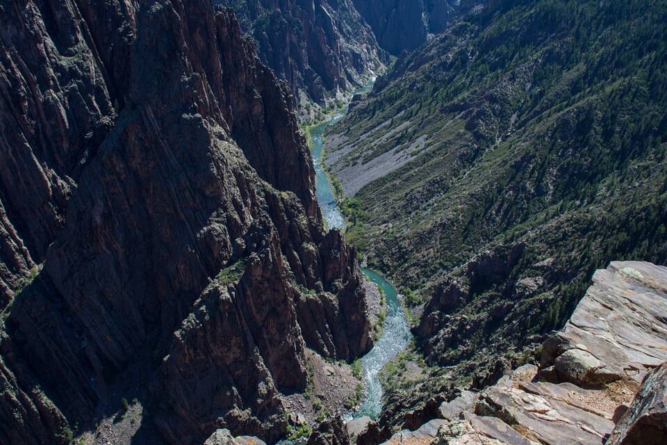 A canyon with a river, rocky cliffs, and green vegetation.